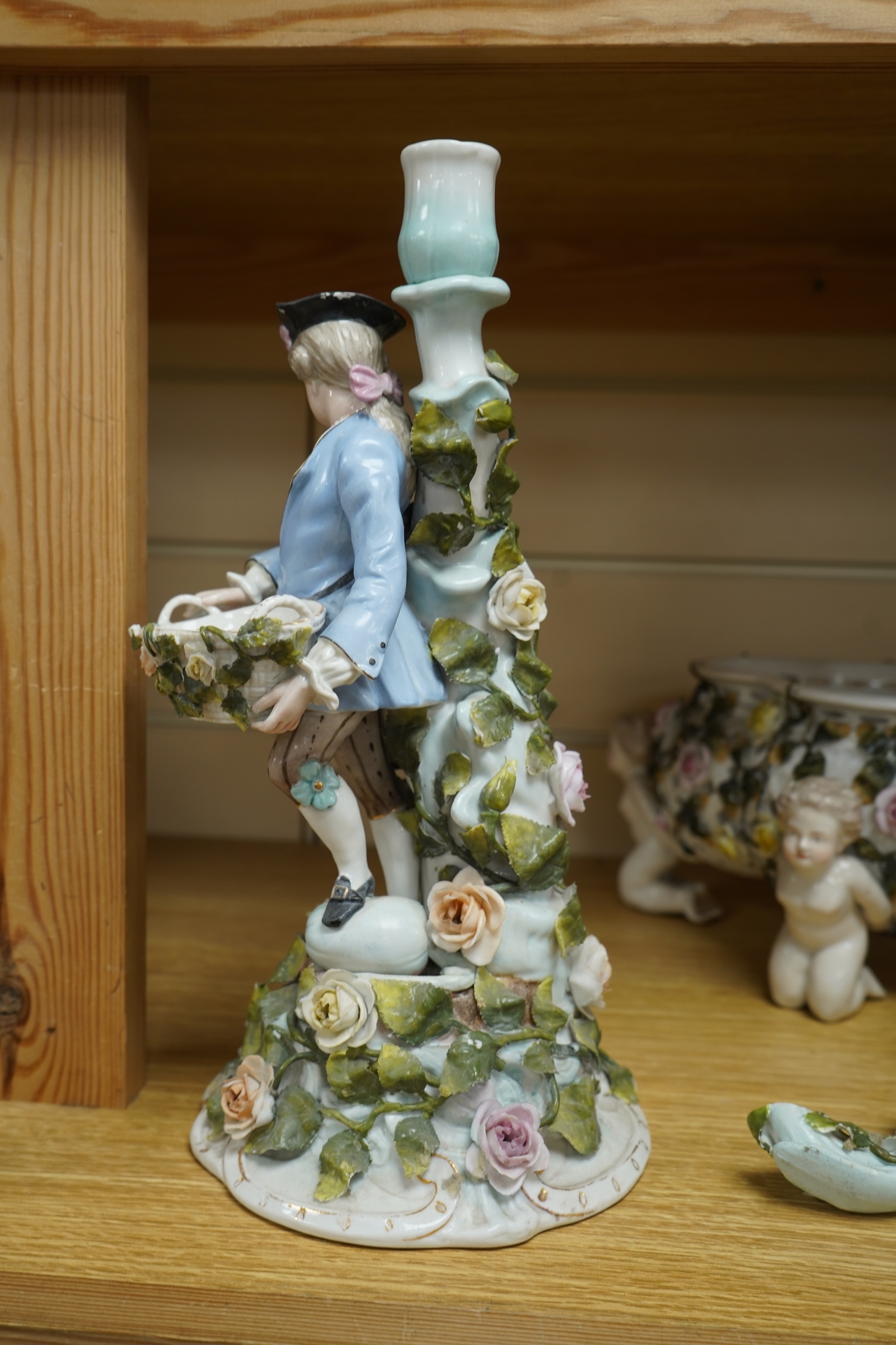 A German flower encrusted porcelain figural candelabrum, 30cm high, a cherub jardiniere and a cherub vase, all encrusted